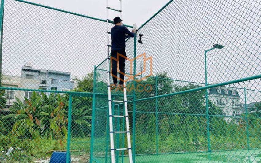Nhân viên Panaco đang lắp camera giám sát trên hàng rào sân tennis