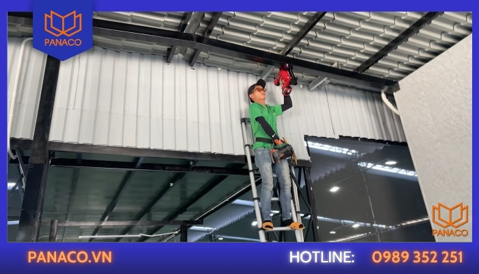 Kỹ thuật viên dùng máy bắn đinh cố định hệ thống dây camera trên cao