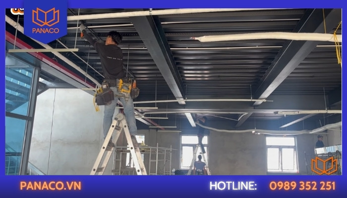 Kỹ thuật viên thi công đi ống bảo vệ đường dây camera trên trần